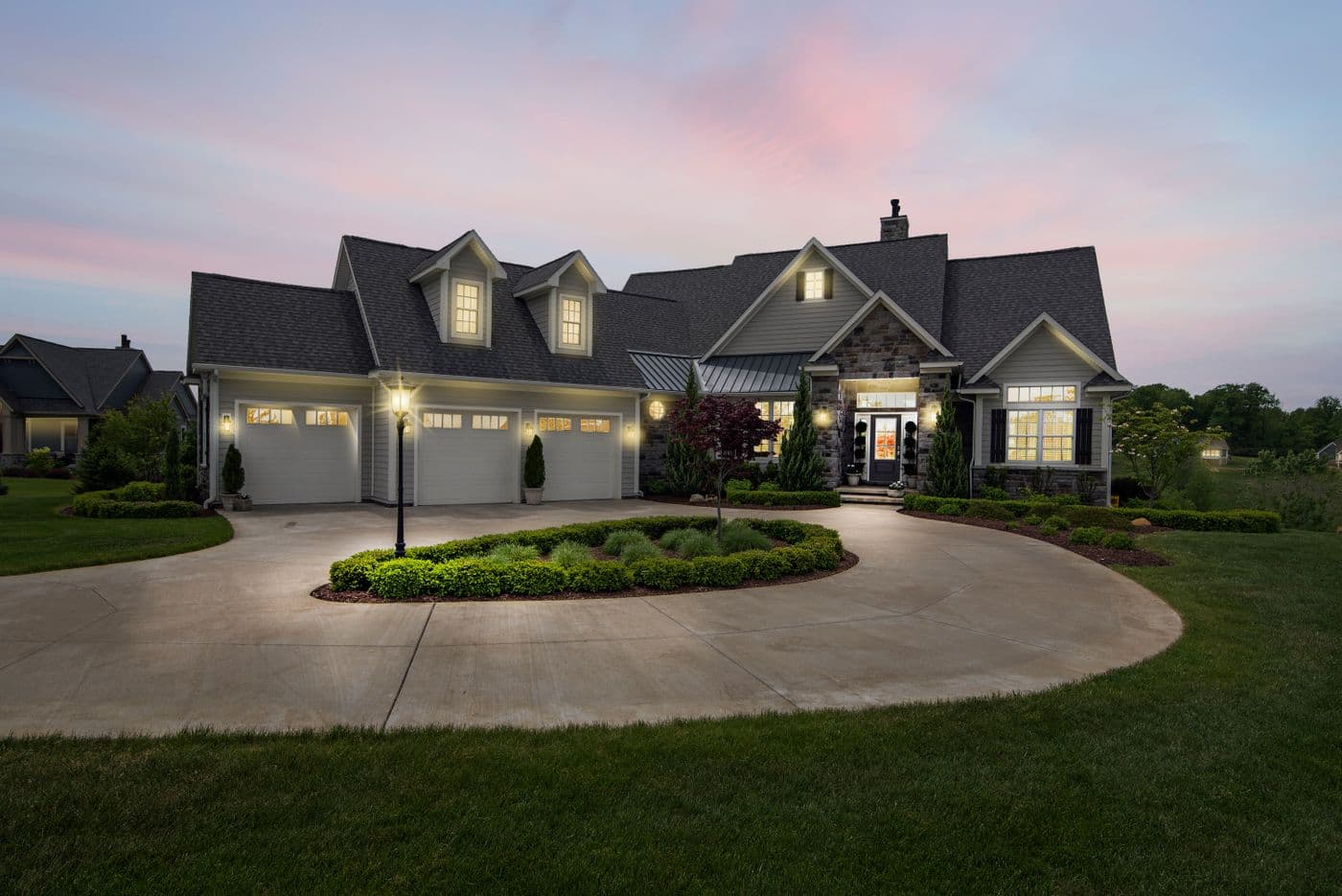 Suburban home at dusk with exterior landscape and garage lighting