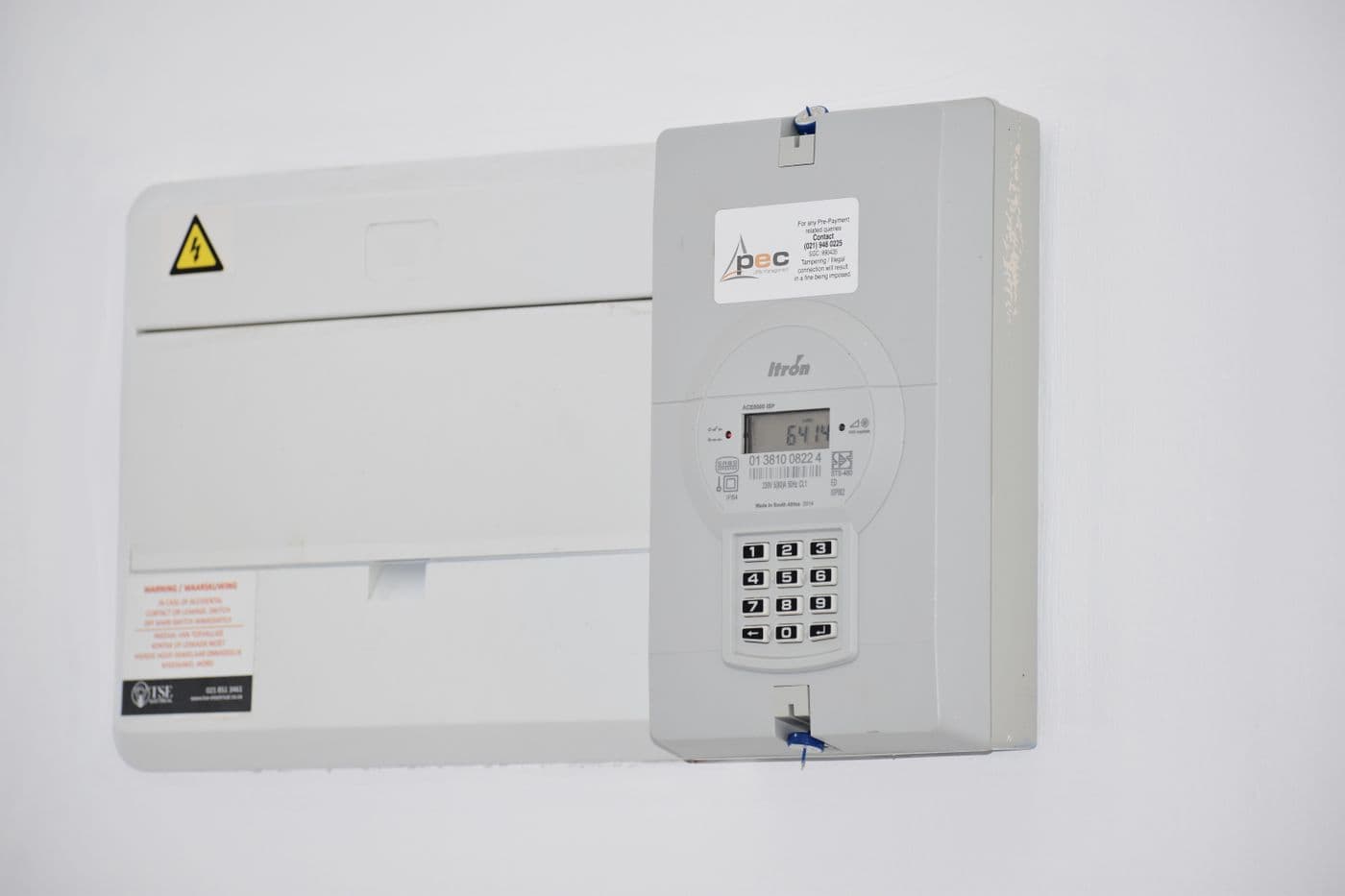 Electrical meter and fuse box mounted on a white wall